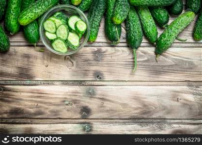 Cucumbers and cucumber slices in a glass bowl. On wooden background. Cucumbers and cucumber slices in a glass bowl.
