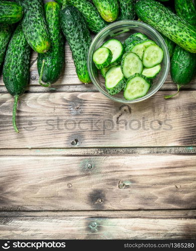 Cucumbers and cucumber slices in a glass bowl. On wooden background. Cucumbers and cucumber slices in a glass bowl.