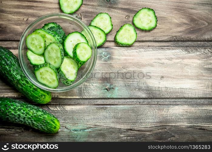 Cucumbers and cucumber slices in a glass bowl. On wooden background. Cucumbers and cucumber slices in a glass bowl.