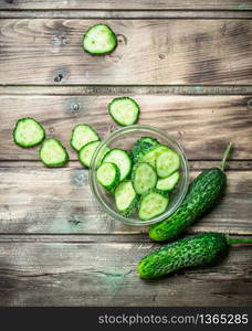 Cucumbers and cucumber slices in a glass bowl. On wooden background. Cucumbers and cucumber slices in a glass bowl.