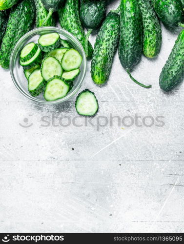 Cucumbers and pieces of fresh cucumbers in the bowl. On rustic background. Cucumbers and pieces of fresh cucumbers in the bowl.