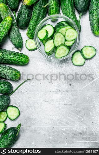 Cucumbers and pieces of fresh cucumbers in the bowl. On rustic background. Cucumbers and pieces of fresh cucumbers in the bowl.