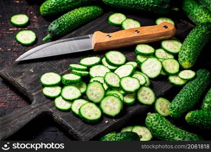 Cucumbers cut on a cutting board. On a black background. High quality photo. Cucumbers cut on a cutting board.