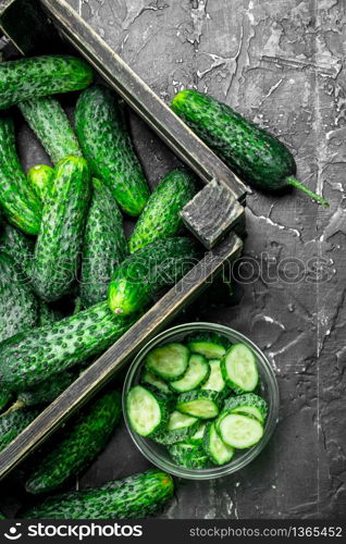 Cucumbers in the box and cucumber slices in the bowl. On rustic background. Cucumbers in the box and cucumber slices in the bowl.