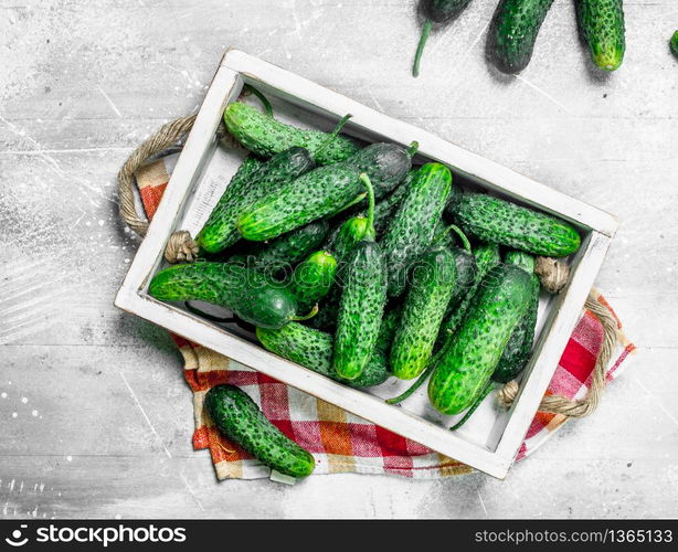 Cucumbers on a wooden tray with a napkin. On white rustic background. Cucumbers on a wooden tray with a napkin.