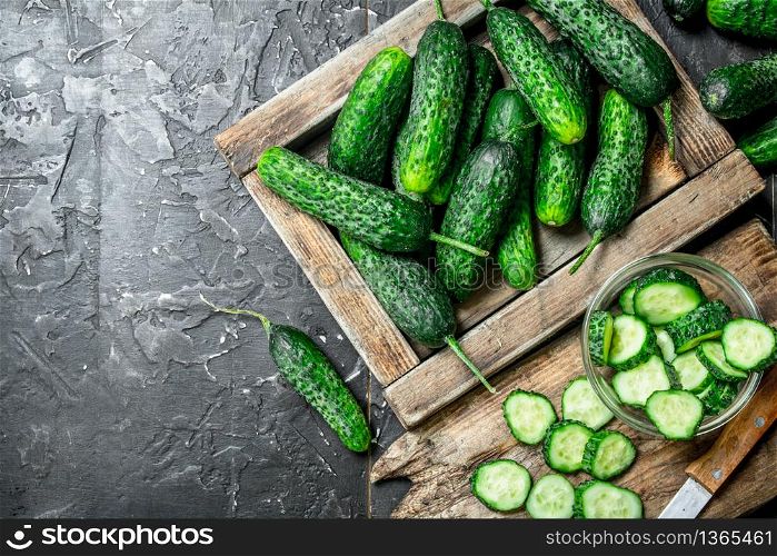 Cucumbers on tray and cucumber slices on a cutting Board with a knife. On rustic background. Cucumbers on tray and cucumber slices on a cutting Board with a knife.