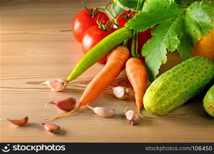Cucumbers, tomatoes, carrots, garlic, zucchini on wooden table. Vegetable background. Copy space.