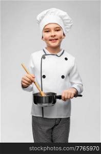 culinary and profession concept - happy smiling little boy in chef’s toque and jacket with saucepan and spoon cooking food over grey background. boy in chef’s toque with saucepan cooking food