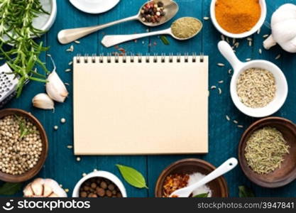 culinary background and recipe book with various spices on wooden table