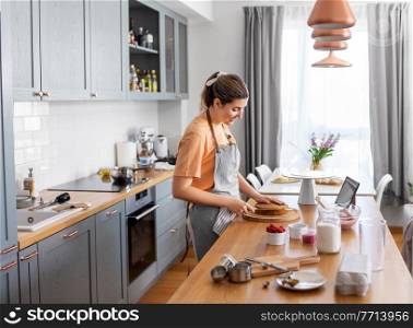 culinary, baking and cooking food concept - happy smiling young woman making cake on kitchen at home. woman cooking food and baking on kitchen at home