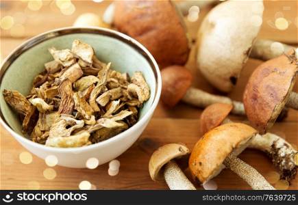 culinary, food and cooking concept - dried mushrooms in bowl on wooden background. dried mushrooms in bowl on wooden background