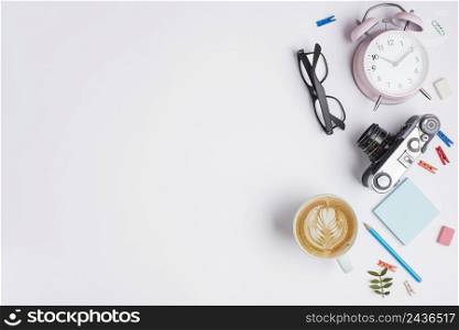 cup cappuccino with latte art vintage camera alarm clock pencil eyeglasses white background