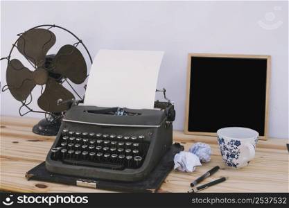 cup chalkboard near typewriter fan