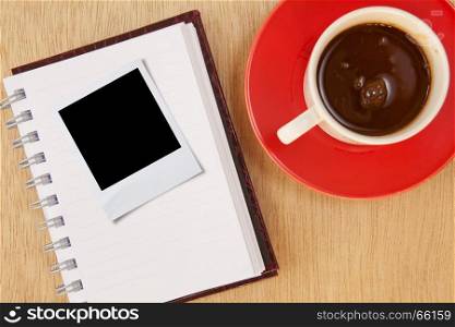cup coffee and photo frame and notebook on wood background