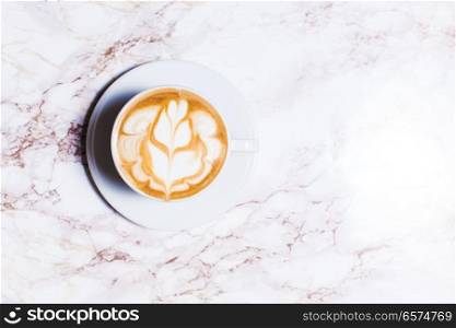cup coffee on wood table in top view. Cup of latte art coffee with flower on marble table
