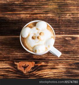 cup coffee on wood table in top view. Cup cappuccino with latte art - 3d volume bear muzzle on wood table