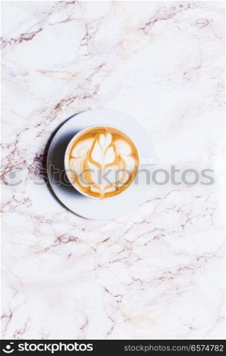 cup coffee on wood table in top view. Cup of latte art coffee with flower on marble table