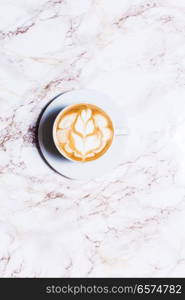 cup coffee on wood table in top view. Cup of latte art coffee with flower on marble table