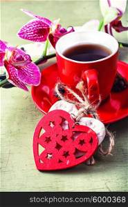 Cup decorated with symbolic hearts with black coffee and flowering branch of orchids
