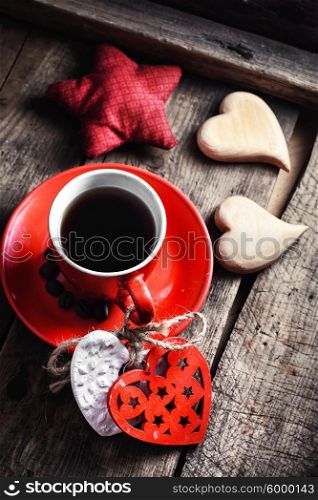 Cup decorated with wooden hearts. Red Cup with black coffee and two carved decorative wooden heart.Selective focus