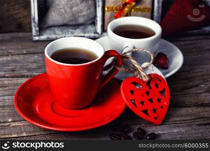 Cup decorated with wooden hearts. Red mug with black coffee and two carved decorative wooden heart.Selective focus