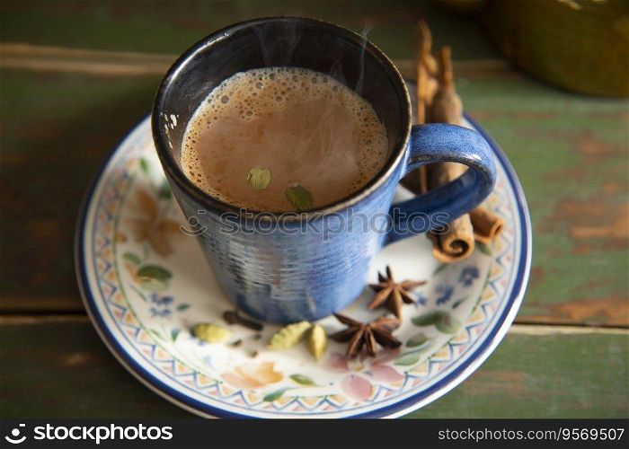 Cup filled with hot tea kept on a saucer next to it's spices