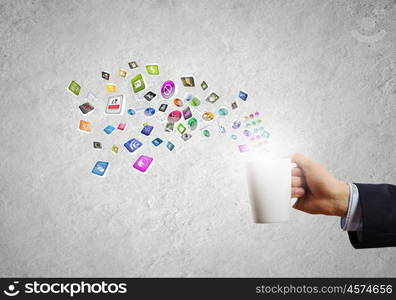 Cup in hand. Close up of businessman holding white cup with icons flying out