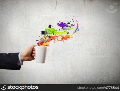 Cup in hand. Close up of businessman holding white cup with icons flying out