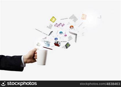 Cup in hand. Close up of businessman holding white cup with icons flying out