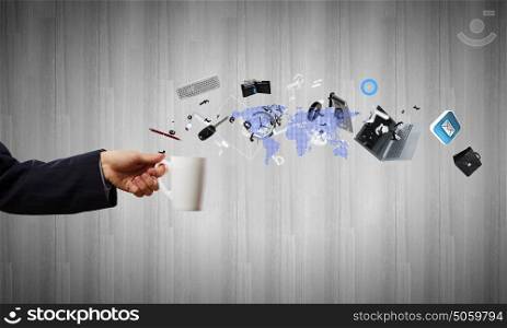 Cup in hand. Close up of businessman holding white cup with icons flying out