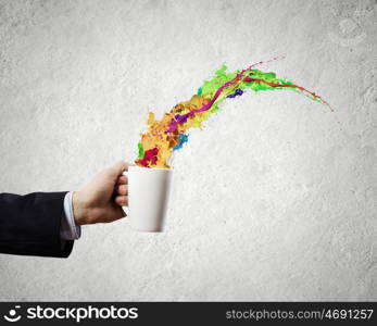 Cup in hand. Close up of businessman holding white cup with splashes flying out