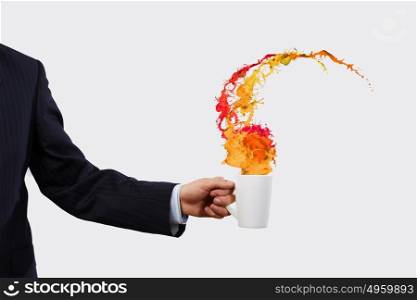 Cup in hand. Close up of businessman holding white cup with splashes flying out