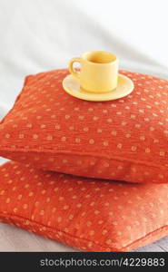 cup lying on pillows on the bed