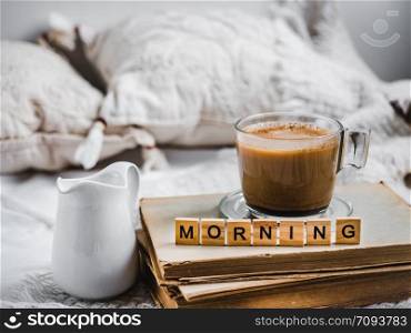 Cup of aromatic coffee, creamer with fresh milk, old books, pillows and a plaid. Breakfast in the early, sunny morning. Cup of aromatic coffee, creamer with fresh milk