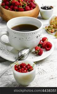 Cup of berry tea. Mug with fragrant summer tea with fruits of raspberry and currant