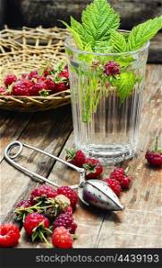 Cup of berry tea. summer tea with fruits of raspberry in faceted glass