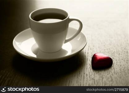 Cup of black coffee and a chocolate heart