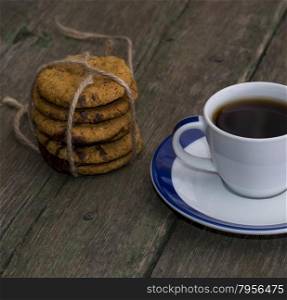 cup of black coffee and linking of cookies on the old desktop