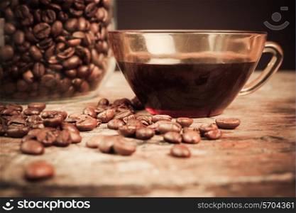 Cup of black coffee next to a jar filled with coffee beans