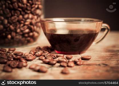 Cup of black coffee next to a jar filled with coffee beans