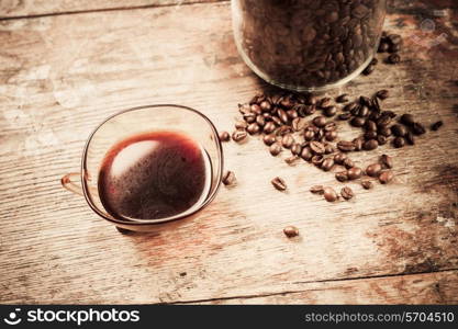 Cup of black coffee next to a jar filled with coffee beans