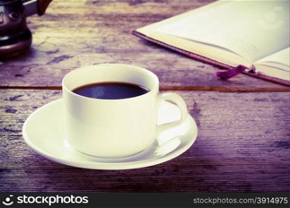 Cup of black coffee with a book on a wooden table