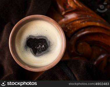 cup of black coffee with foam on dark wooden background, top view, close up