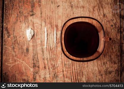 Cup of black coffee with lines of cocaine next to it on table