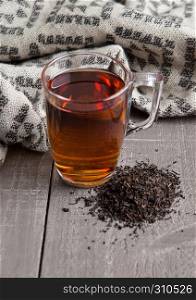 Cup of black healthy tea scarf and loose tea on wooden background