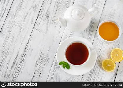 Cup of black tea with honey and lemon on wooden background: top view
