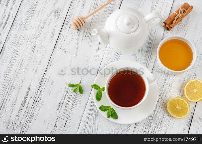 Cup of black tea with honey, lemon and spices on wooden background  top view