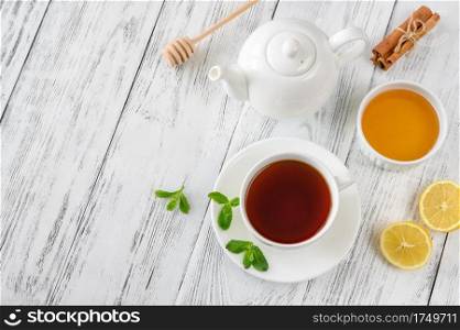 Cup of black tea with honey, lemon and spices on wooden background: top view
