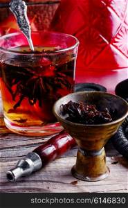 Cup of brewed herbal tea from rose and Turkish hookah. Hookah and tea