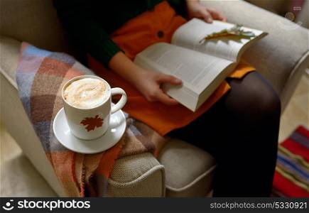 Cup of cappuccino coffee and girl reading a book